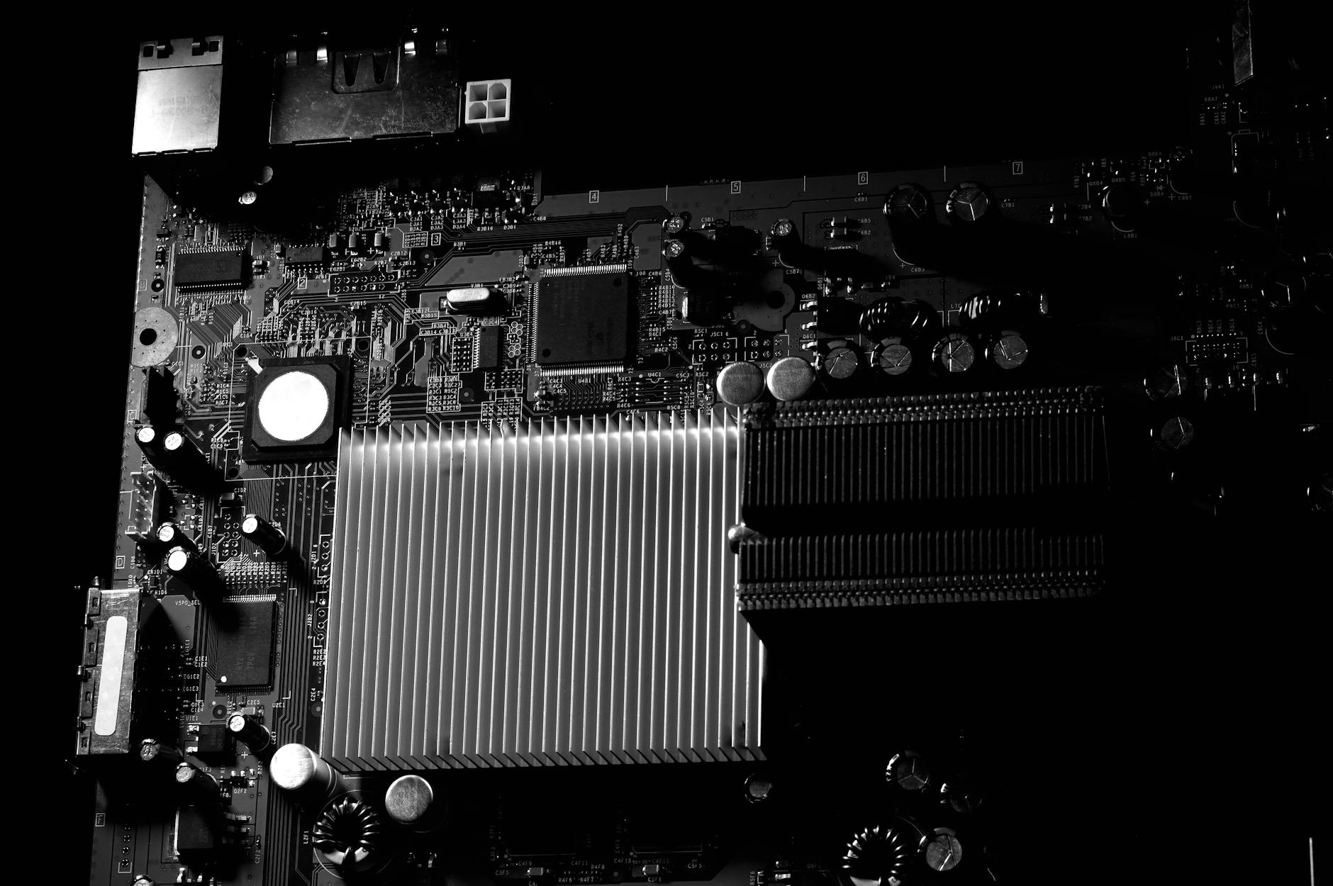 Detailed black and white photo of a computer motherboard highlighting the heatsink.